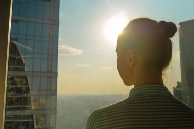Gökdelen penceresinden şehir manzarasına bakan kadın siluetinin arka planı