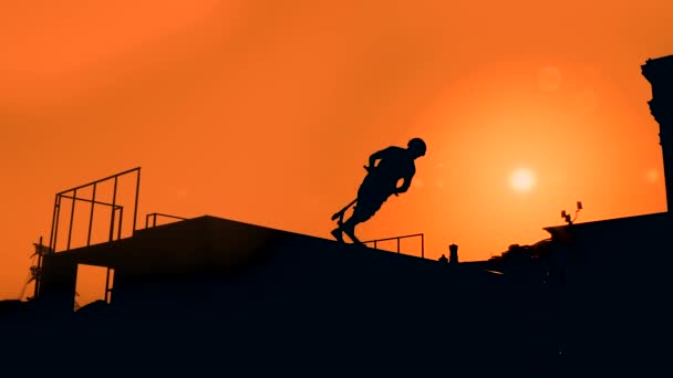 Wolny ruch: sylwetka nastolatka pokazująca sztuczki skoku na skuterze o zachodzie słońca — Wideo stockowe