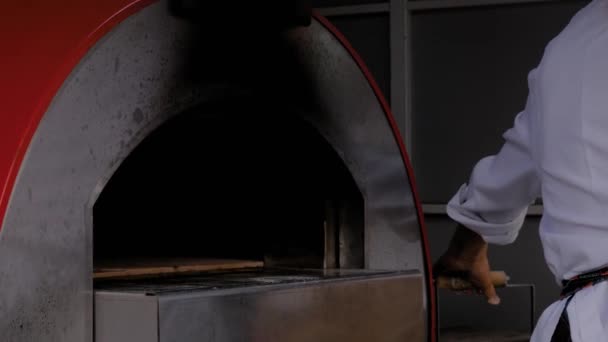 厨师，烘培师，把披萨放进现代金属烤箱，关门 — 图库视频影像