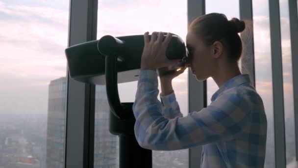 Cámara lenta - mujer mirando a través del telescopio turístico y explorando el paisaje urbano — Vídeos de Stock