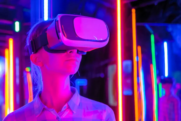 Young woman using virtual reality headset at dark interactive VR exhibition