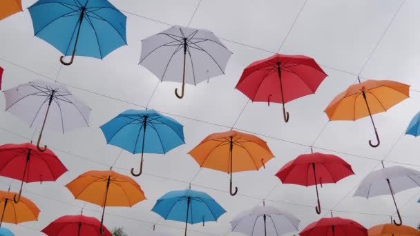 Cámara lenta: paraguas coloridos colgando contra el cielo nublado en el festival al aire libre — Vídeos de Stock