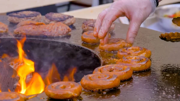 Chef grelhando salsichas de porco em espiral fresco no braseiro com chama quente — Fotografia de Stock