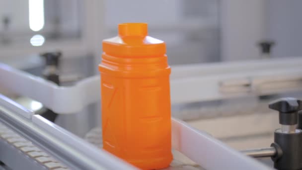 Close up: lege oranje plastic jerrycans bewegen op transportband op tentoonstelling — Stockvideo