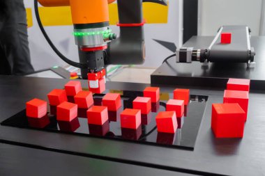 Robot kol manipülatörü robot sergisinde kırmızı oyuncak bloklarını hareket ettiriyor ve yerleştiriyor