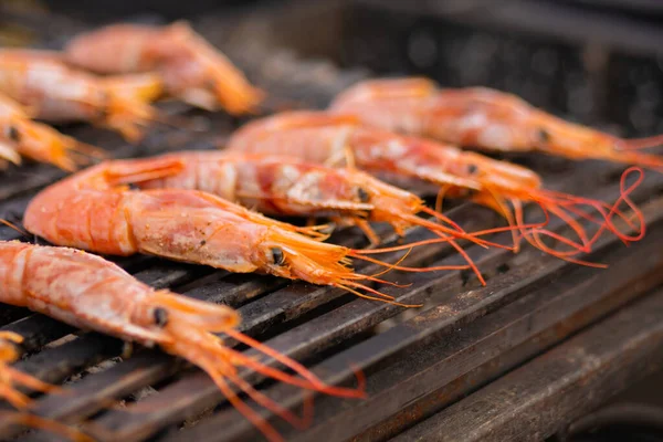 Process of cooking fresh red langoustine shrimps, prawns on grill - street food
