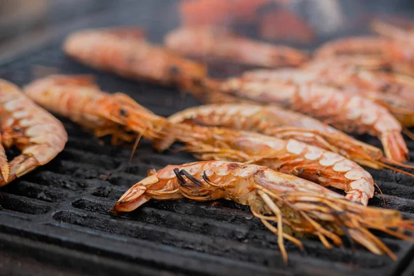 Process of cooking fresh red langoustine shrimps, prawns on grill - street food