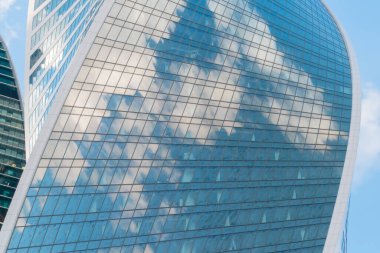 Beyaz bulutların yansıması ve mavi gökyüzü modern gökdelenlerin cam duvarında
