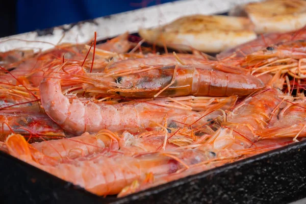 Process of cooking fresh red langoustine shrimps, prawns on grill - street food