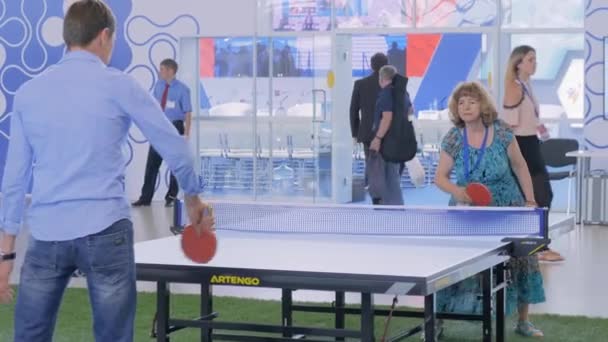 Jovem e mulher idosa jogando ping pong tênis de mesa na exposição esportiva — Vídeo de Stock