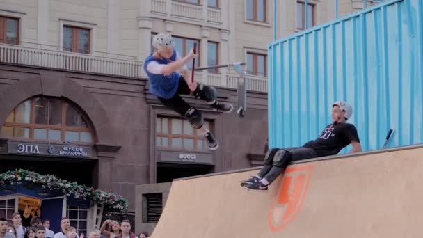 Remaja laki-laki menunjukkan melompat trik atas orang-orang pada skuter di skatepark — Stok Video
