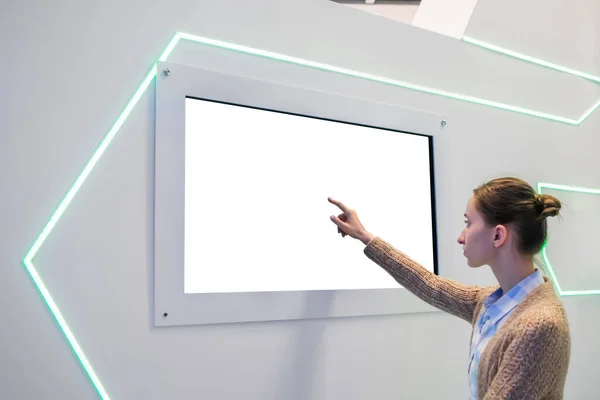 Woman touching blank white display wall at exhibition - white screen concept