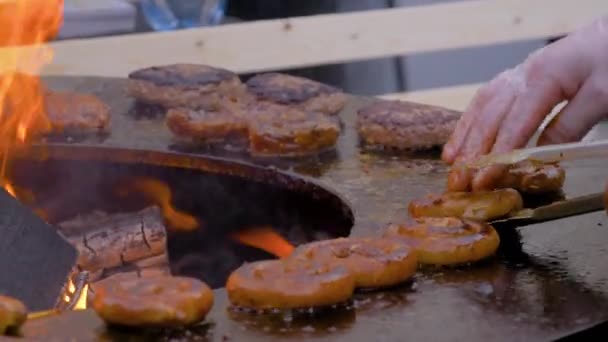 Повільний рух: шеф-кухар смажить свіжі спіральні свинячі ковбаски на мангалі з гарячим полум'ям — стокове відео