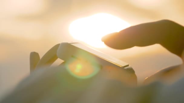 Mujer que usa reloj inteligente blanco portátil contra el cielo cálido al atardecer - cámara lenta — Vídeos de Stock