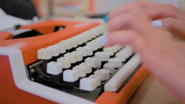 Close up view: woman typing on old vintage orange typewriter on table — Stock Video