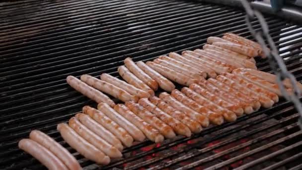 Chef asar salchichas de carne fresca en la gran parrilla redonda colgante al aire libre — Vídeo de stock