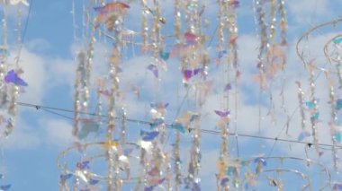 Parlak asılı kelebek süslemesi rüzgarda sallanıyor bulutlu mavi gökyüzüne karşı