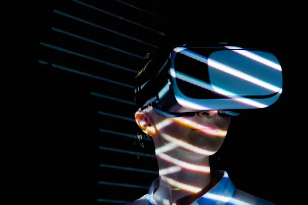 Young woman using virtual reality headset at dark interactive VR exhibition