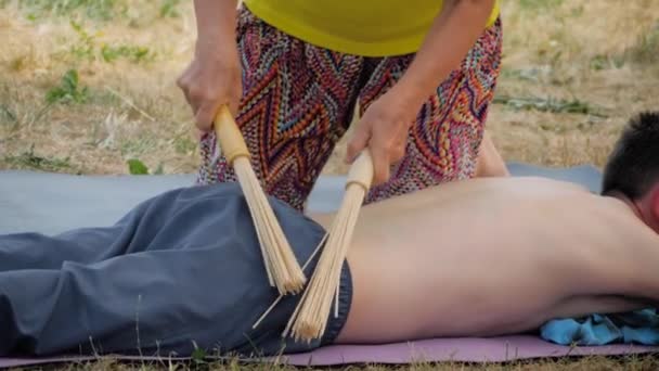 Tangan wanita melakukan pijat untuk pria dengan tongkat bambu di festival yoga luar ruangan — Stok Video