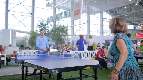 Junger Mann und ältere Frau spielen Tischtennis bei Sportausstellung — Stockvideo