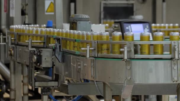 Перемещение желтых алюминиевых пивных банок на конвейерной ленте на пивоваренном заводе — стоковое видео
