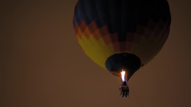 Colorido globo de aire caliente volando con llamas contra el cielo oscuro por la noche — Vídeo de stock
