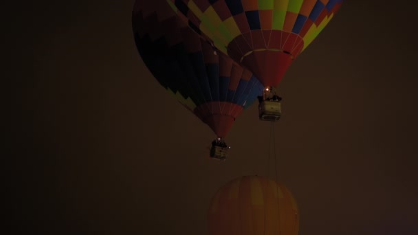 Balões de ar quente coloridos voando com chamas contra o céu escuro — Vídeo de Stock