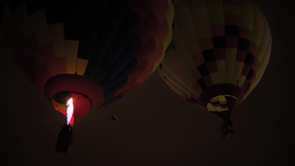 Dwa kolorowe balony z gorącym powietrzem lecące z płomieniami przeciwko ciemnemu niebu — Wideo stockowe