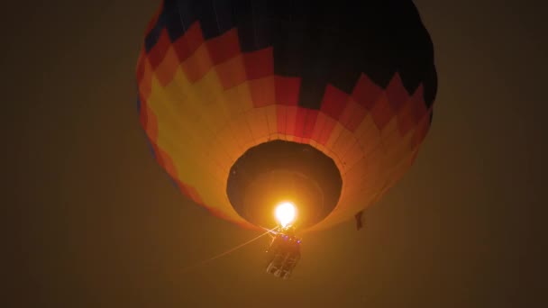 Bunter Heißluftballon fliegt nachts mit Flammen gegen dunklen Himmel — Stockvideo