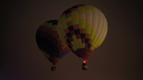 Dois balões coloridos de ar quente voando com chamas contra o céu escuro — Vídeo de Stock