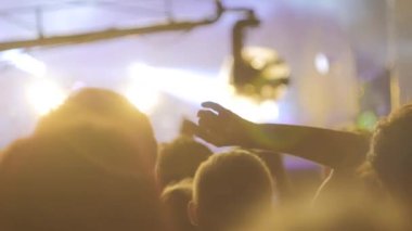 Yavaş çekim: insanlar sahnenin önündeki rock konserinde parti yapıyor ve zıplıyorlar