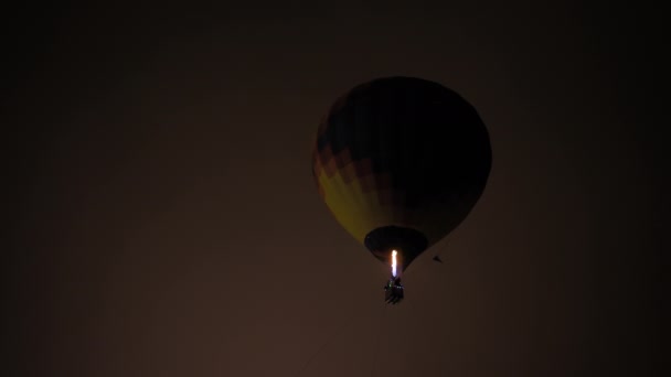 Balão de ar quente colorido voando com chamas contra o céu escuro à noite — Vídeo de Stock