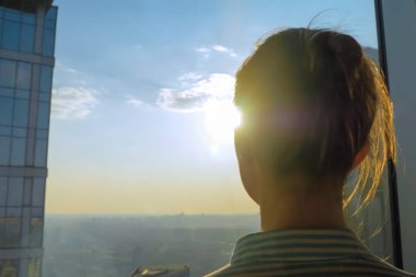 Gökdelenin cam penceresinden şehir manzarasına bakan kadının arka planı