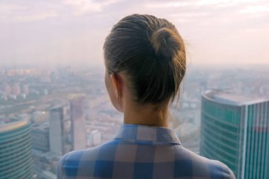 Gökdelen penceresinden şehir manzarasına bakan kadının arka planı