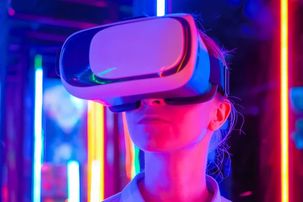 Young woman using virtual reality headset at dark interactive VR exhibition