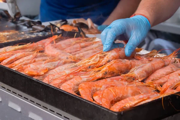 Chef cooking fresh red langoustine shrimps, prawns on grill at summer local food