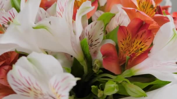 Zamknij: bukiet pomarańczowych i białych kwiatów alstroemerii na obracającej się powierzchni — Wideo stockowe