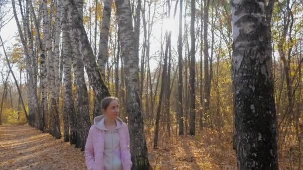 Junge Frau spaziert durch Herbstpark - Steadicam-Aufnahme, Sonnenbrille leuchtet — Stockvideo