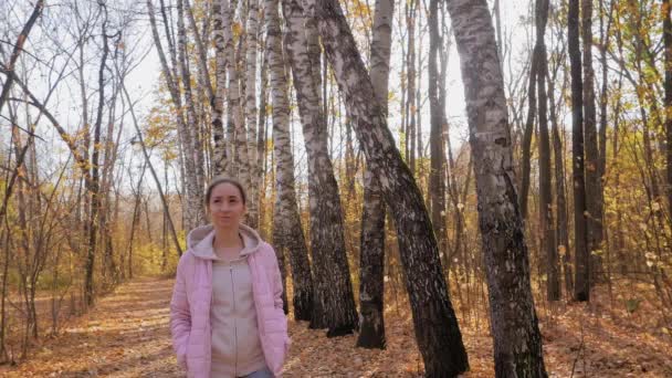 Cámara lenta: mujer joven caminando en el parque de otoño, disparo steadicam, destellos de lentes de sol — Vídeos de Stock