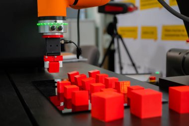 Robot kol manipülatörü robot sergisinde kırmızı oyuncak bloklarını hareket ettiriyor ve yerleştiriyor