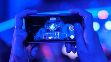 Akıllı telefonlu canlı müzik konserinin görüntülerini kaydeden eller.
