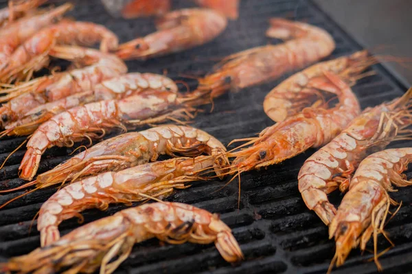 Process of cooking fresh red langoustine shrimps, prawns on grill - street food