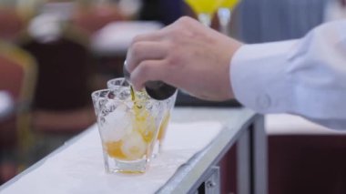 Barmen bar tezgahında alkollü kokteyl yapıyor. Yakın çekim.