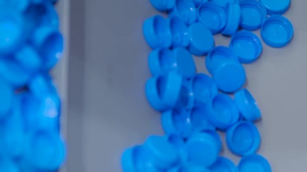 Viele blaue Plastikflaschenverschlüsse bewegen sich auf Förderband - Produktionslinie — Stockvideo