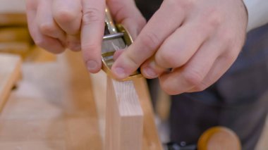 Marangoz ahşap tahtayı şekillendirmek için sözcü ya da uçak kullanıyor.