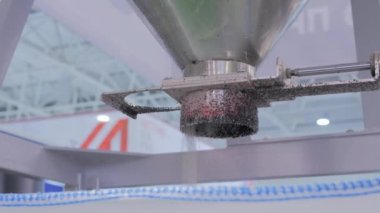 Geri dönüştürülmüş plastik tanecikler, metal kaplara düşen topaklar.