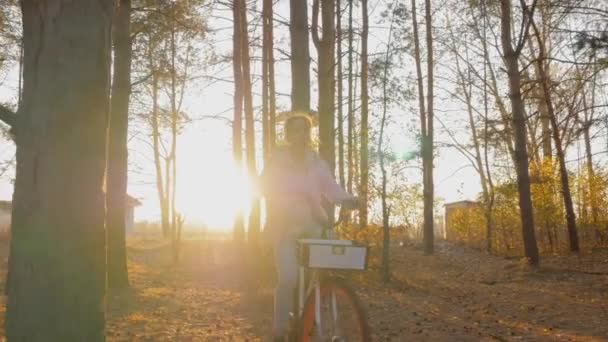 Slow motion: vrouw fietsen in de herfst stadspark bij zonsondergang - vooraanzicht — Stockvideo