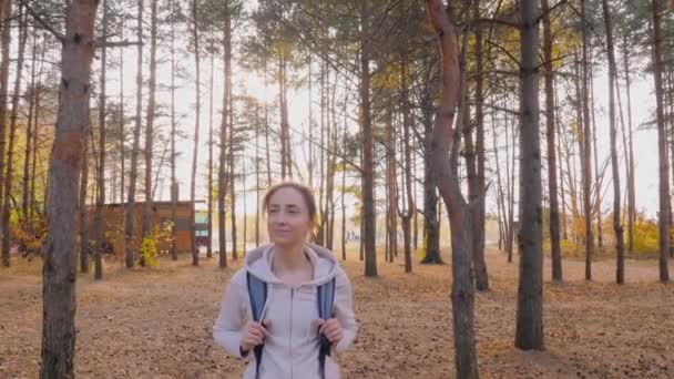 Vista frontal de la joven con mochila caminando en el parque de otoño - steadicam shot — Vídeo de stock