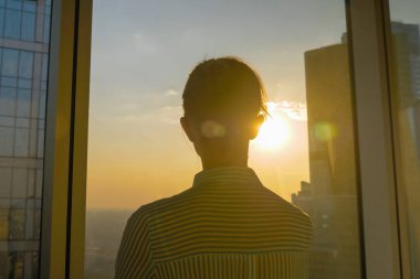 Gökdelenin cam penceresinden şehir manzarasına bakan kadının arka planı