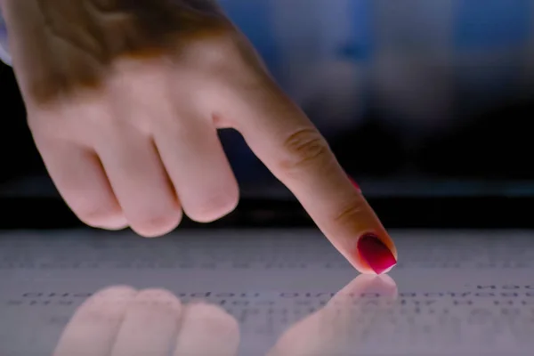 Woman finger using multimedia touchscreen display of interactive kiosk: close up